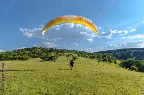 Man running down the hill with parachute , gorgeous nature background and beautiful skies 