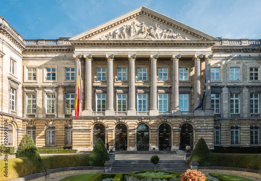 Brussels, Belgium - September 26, 2018: Closeup of front Facade of Belgian Parliament in romanesque style with pillars and fresco triangle, and  Belgian and European flag.