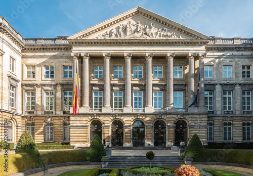 Brussels, Belgium - September 26, 2018: Closeup of front Facade of Belgian Parliament in romanesque style with pillars and fresco triangle, and Belgian and European flag.