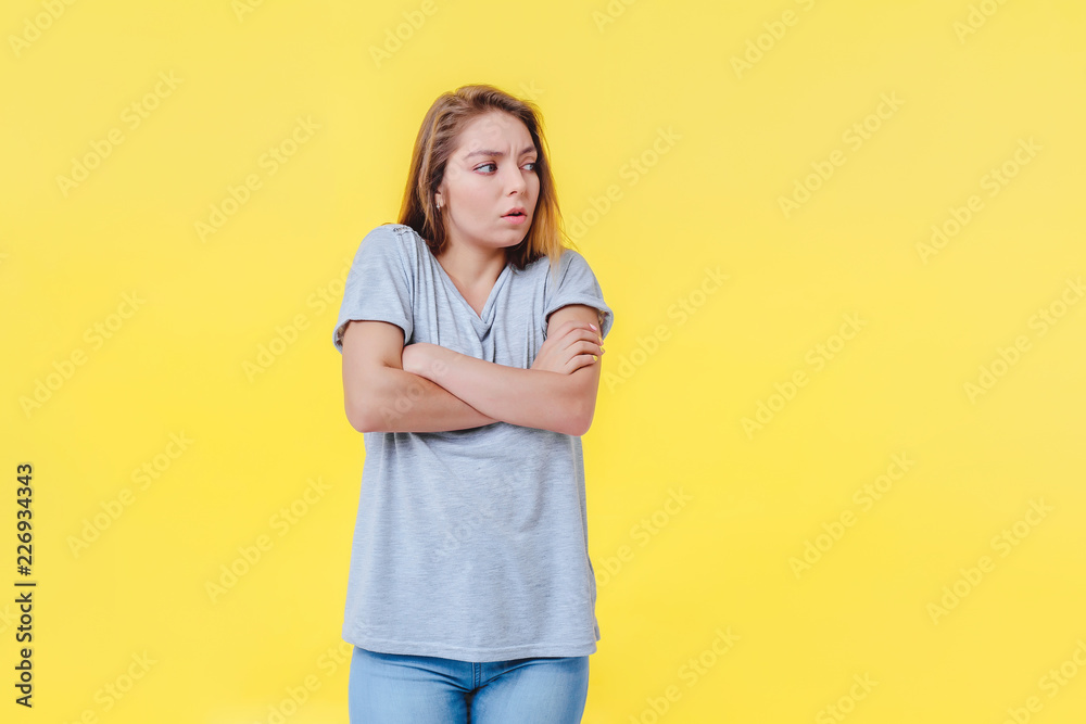 Young сaucasian girl on a yellow background looks away incredulously. Concept of non-acceptance and alienation of services. Young сaucasian girl on a yellow background looks away incredulously. Concept of non-acceptance and alienation of services.