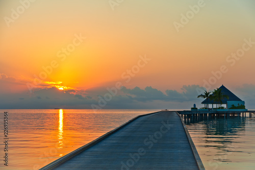 Wooden pier at tropical island resort at sunset time, Maldives. Vacations And Tourism Concept
