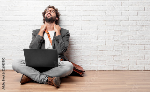 young man sitting on the floor looking unenthusiastic and bored, listening to something dull and tedious and feeling like bearing a drag. photo