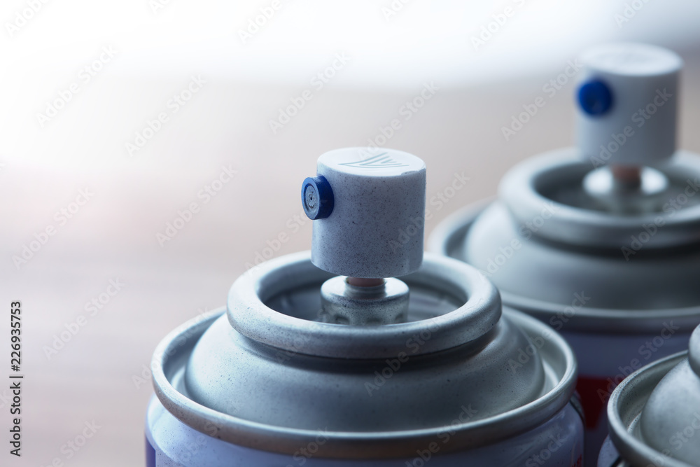 Aerosol spray cans nozzle close up. Several spray cans with light in background. Shallow depth of field. Aerosol spray cans nozzle close up. Several spray cans with light in background. Shallow depth of field.