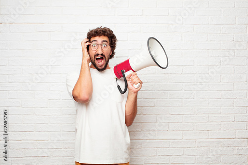 young dumb man with a crazy, amazed look of surprise, holding head with both hands, pulling hair. photo