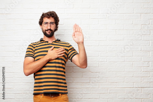 Принти на полотні young dumb man smiling confidently while making a sincere promise or oath, solemnly swearing with one hand over heart