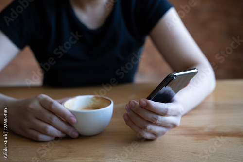 female model holds modern smart phone relaxing in cafe coffee