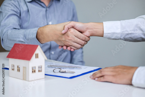 Real estate agent and customers shaking hands together celebrating finished contract after signing about home insurance and investment loan, handshake and successful deal