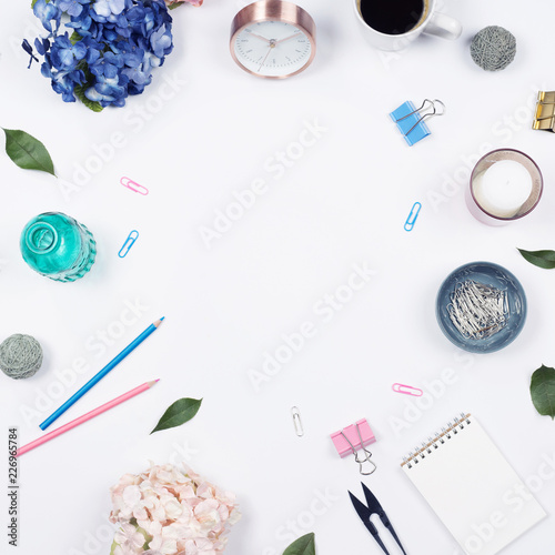 Feminine desk workspace frame with beauty arrangement of bouquet hydrangeas, laptop, clipboard, notebook, pencil and candle on white background. Flat lay, Top view office table desk with copy space. 