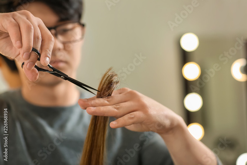 Professional hairdresser working with client in beauty salon