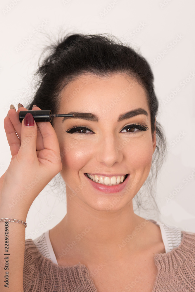 Sensual brunette model smiling with casual look being eyebrow styled during makeup session Sensual brunette model smiling with casual look being eyebrow styled during makeup session