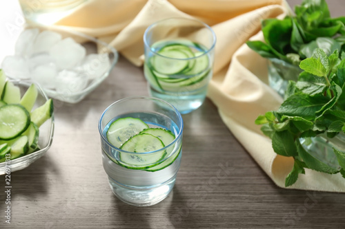 Glass of tasty fresh cucumber water on wooden table