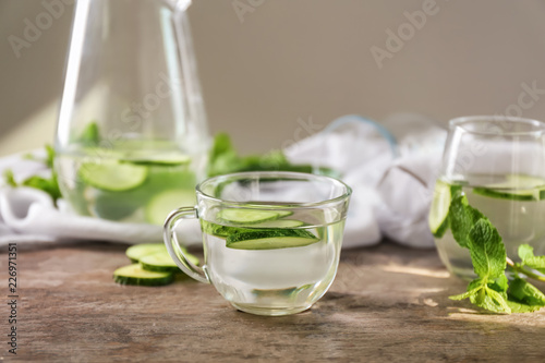 Glass cup of tasty fresh cucumber water on wooden table