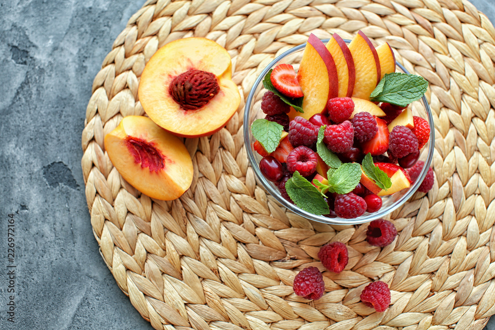 Glass bowl with delicious fruit salad on wicker mat
