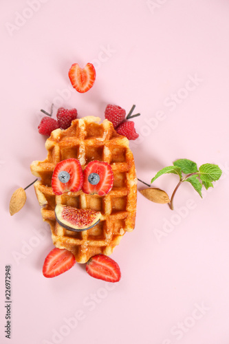 Creative composition with delicious waffle and berries on color background