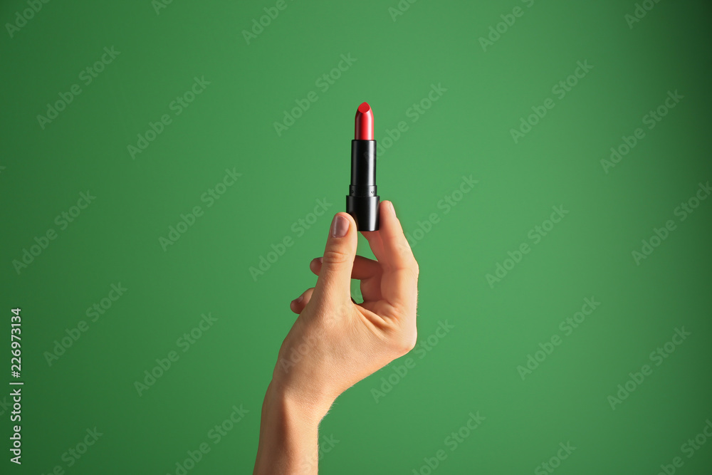Woman holding bright lipstick on color background Woman holding bright lipstick on color background