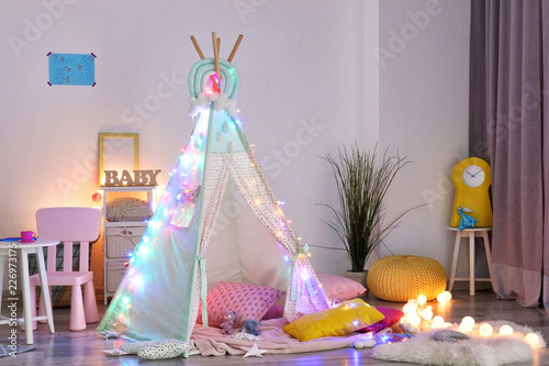 Cozy play tent for kids with glowing garland in room interior photo