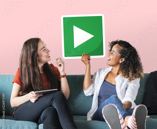 Female friends holding a play button