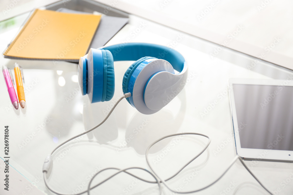 Headphones with tablet PC and stationery on glass table
