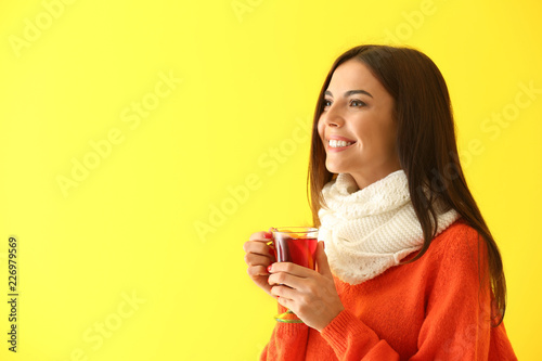 Woman with glass cup of delicious mulled wine on color background