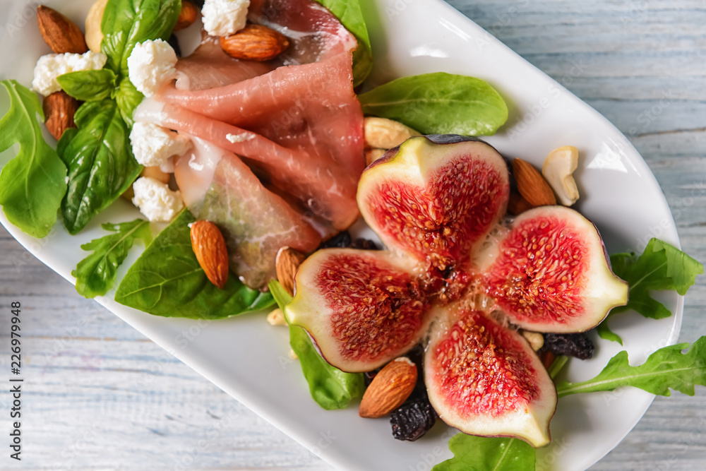 Plate with delicious fig salad on light wooden table