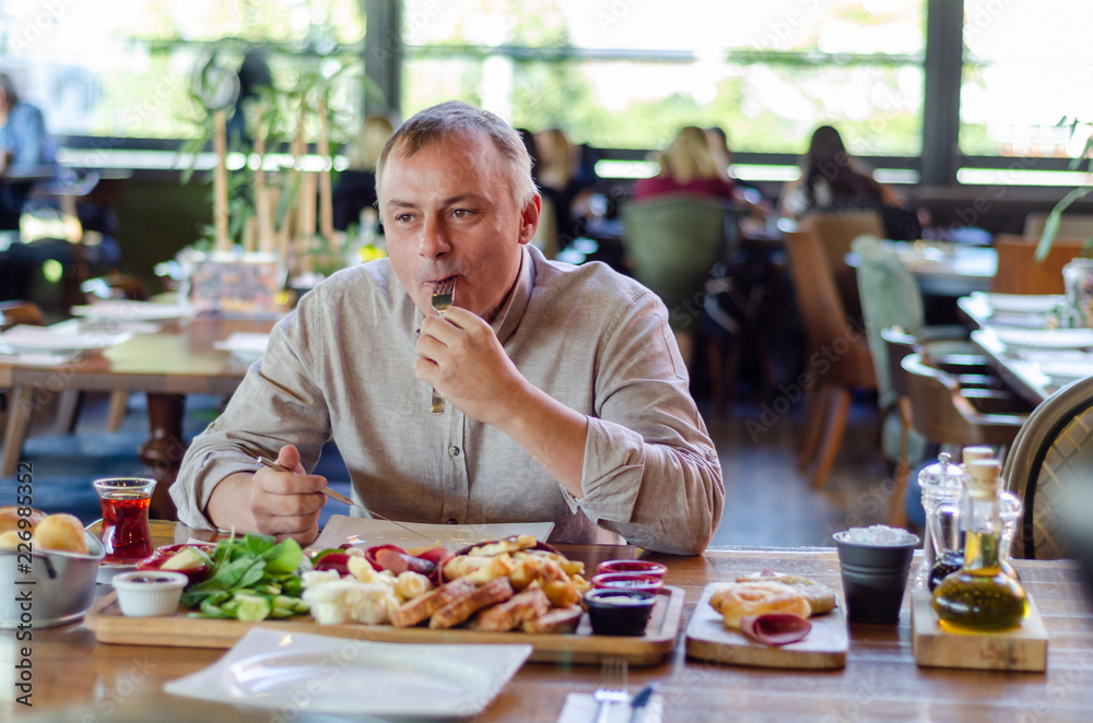 The man is eating breakfast in the restaurant. The man is eating breakfast in the restaurant.