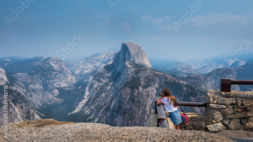 view of half dome at yosemite national park with young tourist taking a photo