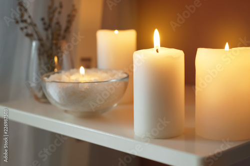 Beautiful burning candles on shelf indoors