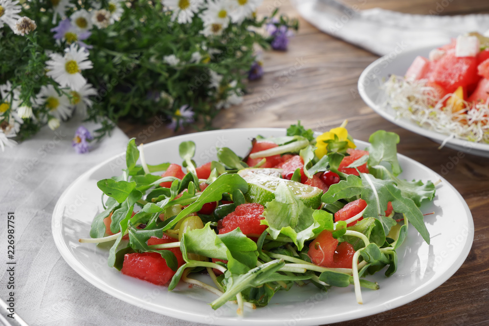 Plate with delicious watermelon salad on wooden table