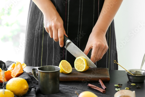 Woman cutting lemon for mulled wine at table