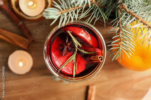 Glass of delicious mulled wine on wooden board