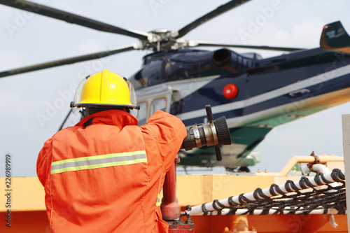Helicopter Landing Officer communicating with pilot and copilot for service on ground and support as the pilot required. The helicopter landing on the deck in oil and gas platform.