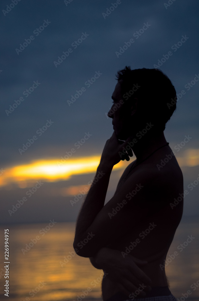 Man silhouette at sunset near the sea. he dreams and thinks about romance Man silhouette at sunset near the sea. he dreams and thinks about romance