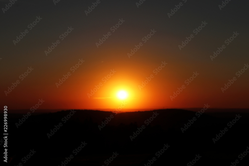 A horizontal beautiful orange sunset with black mountains
