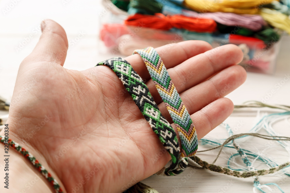 Hand holding different woven friendship bracelet, closeup shot