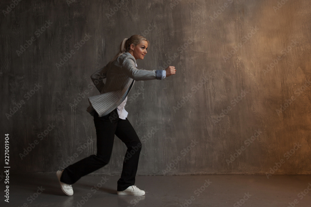 Young woman in business suit and sneakers. runner's pose, ready to run a long distance Young woman in business suit and sneakers. runner's pose, ready to run a long distance