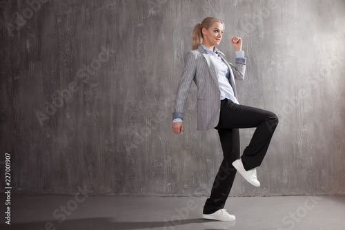 Young woman in business suit and sneakers. runner's pose, ready to run a long distance © Ulia Koltyrina