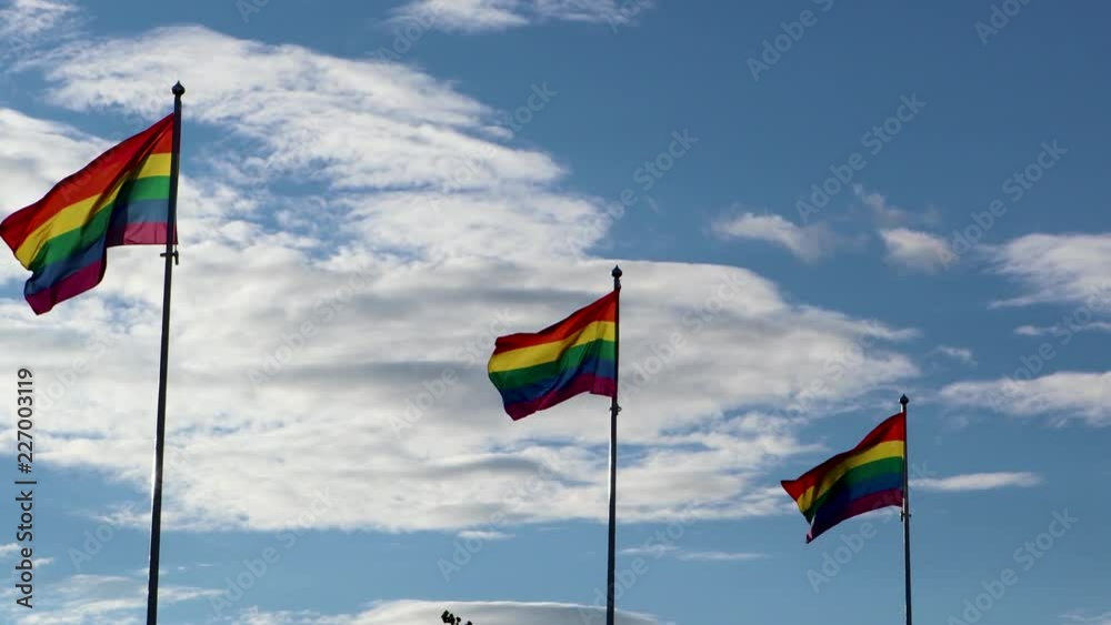 Three rainbow flags evolving in the wind against a blue sky on a sunny day. LGBT community. Three rainbow flags evolving in the wind against a blue sky on a sunny day. LGBT community.