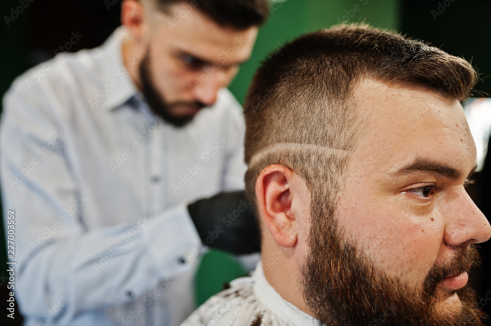 Fototapeta premium Handsome bearded man at the barbershop, barber at work.