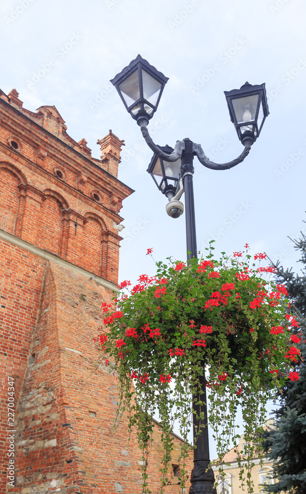 Decorated with flowers street lamp next to  town hall on Old Town Square in Sandomierz, Poland