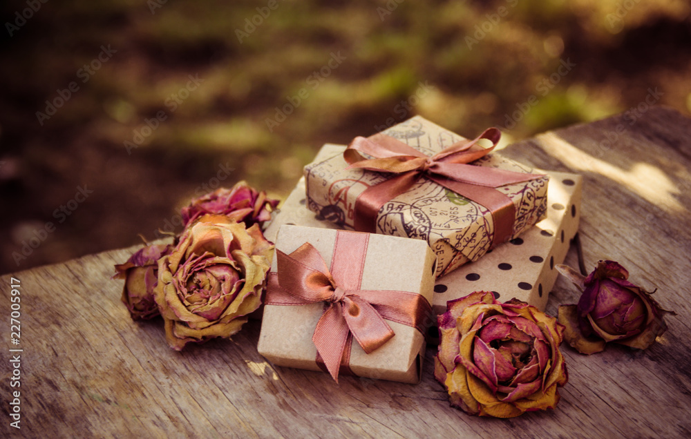Gift boxes and dry roses. Dried flowers and craft gift box. stack of gifts and dried flowers. Gifts in brown paper