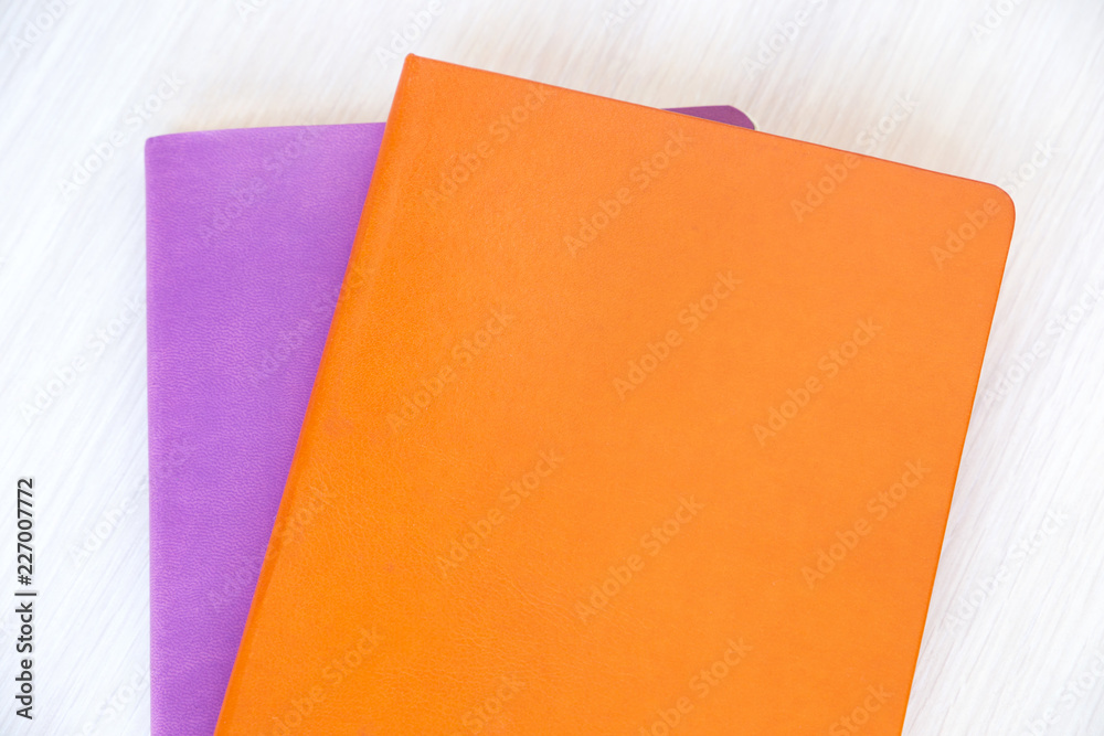 Closeup mockup of the orange and purple books or notebooks with copy space on the table Closeup mockup of the orange and purple books or notebooks with copy space on the table