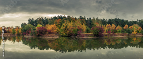 beautiful colorful autumn. picturesque panoramic view of the city park with multicolored trees reflected in the river in cloudy weather