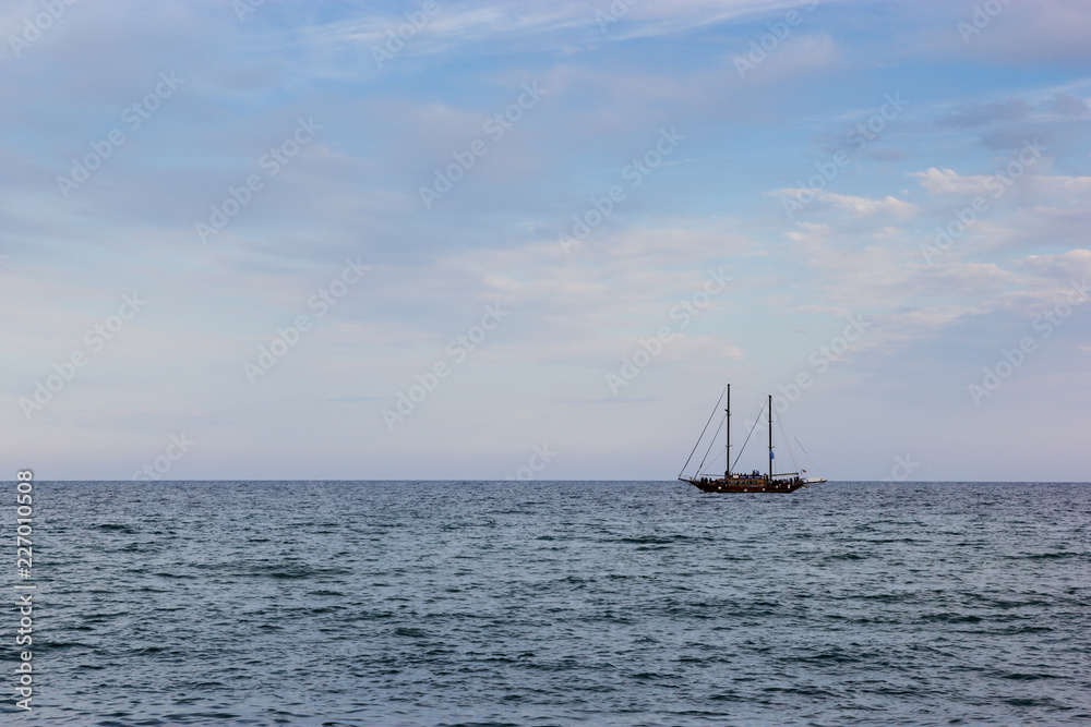 Fototapeta premium A black yacht boat in the sea with cloudy sky