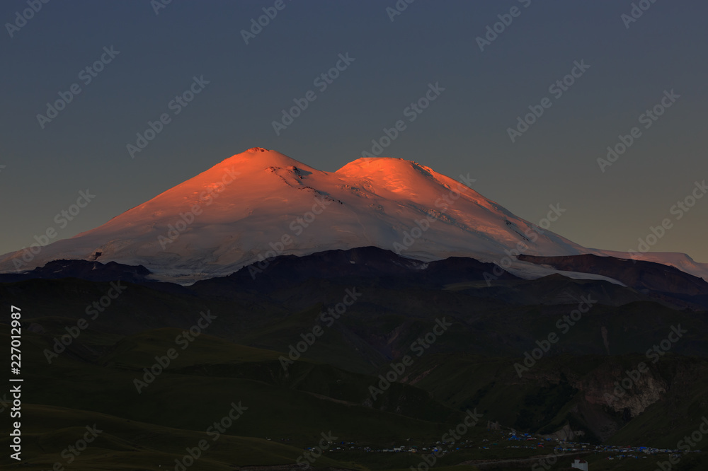 Dawn over the valley at the foot of Mount Elbrus with two snow-capped peaks. Mountain range in the North Caucasus in Russia.