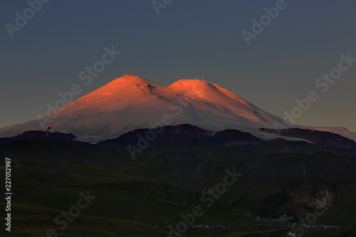 Dawn over the valley at the foot of Mount Elbrus with two snow-capped peaks. Mountain range in the North Caucasus in Russia.