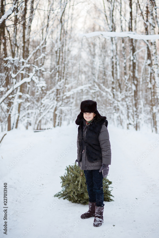 Cute boy with a Christmas tree in his hands, winter, new year, forest