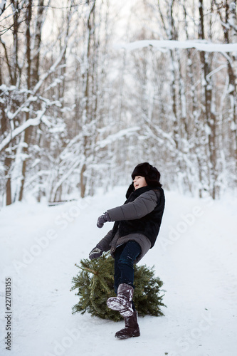 Cute boy with a Christmas tree in his hands, winter, new year, forest