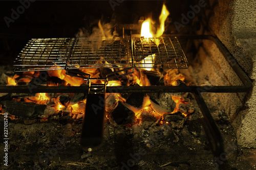 Grill with meat on a flaming charcoal grill with open fire at night. Concept of summer grilling, barbecue, bbq and party. Black copyspace.
