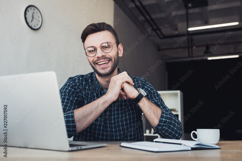portrait of cheerful businessman at workplace with laptop and notebook in office portrait of cheerful businessman at workplace with laptop and notebook in office