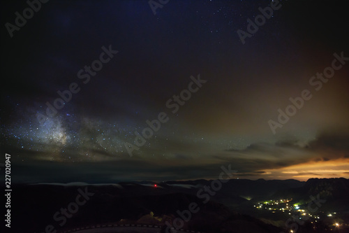 The stars of the Milky Way at night in the sky glow through the clouds. View of outer space in cloudy weather.